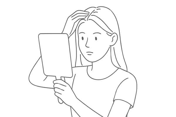 髪の分け目が広がっている女性が鏡を見ている様子